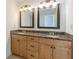 This double-vanity bathroom is detailed with dark granite, light-wood cabinetry, and modern lighting fixtures at 1410 Eastland Rd Se Rd, Atlanta, GA 30316