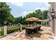 A large back patio with stone floors, manicured landscaping, an outdoor dining set, and a view of the pool at 70 Finch Forest Trl, Atlanta, GA 30327