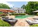 An inviting backyard with a luxurious pool, stone patio, manicured landscaping, and elegant lounge furniture at 70 Finch Forest Trl, Atlanta, GA 30327