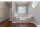 Bathroom featuring a large soaking tub with a shower and a window providing natural light at 10 Briarcliff Pl, Stockbridge, GA 30281