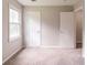 A carpeted bedroom with neutral walls, two closet doors and a window offers a serene and comfortable living space at 10 Briarcliff Pl, Stockbridge, GA 30281