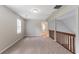 A carpeted bonus room with neutral walls, a wooden railing and natural light offers versatile space at 10 Briarcliff Pl, Stockbridge, GA 30281