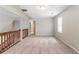 A carpeted bonus room with neutral walls, a wooden railing and natural light offers a functional space at 10 Briarcliff Pl, Stockbridge, GA 30281