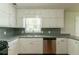 Galley kitchen with classic white cabinets, stainless steel appliances, and natural light at 10 Briarcliff Pl, Stockbridge, GA 30281