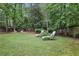 Inviting backyard featuring lounge chairs, a fire pit, and a storage shed surrounded by trees at 3357 Pretty Branch Se Dr, Smyrna, GA 30080