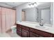 Bathroom features a dark wood vanity, sink, toilet and shower with pink curtain at 5121 Hunters Hill Sw Cv, Lilburn, GA 30047
