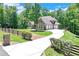 Landscaped front yard with a long driveway leading to a brick home with a three-car garage at 8240 Hurakan Creek Xing, Cumming, GA 30028