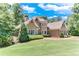 Stunning brick and stone home with manicured landscaping, a lush lawn, and mature trees on a sunny day at 8240 Hurakan Creek Xing, Cumming, GA 30028
