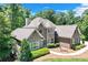 Elegant stone and brick home featuring a manicured lawn, fountain, and lush landscaping at 8240 Hurakan Creek Xing, Cumming, GA 30028