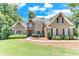 Charming stone home with a well-manicured lawn, mature trees, and beautiful landscaping at 8240 Hurakan Creek Xing, Cumming, GA 30028