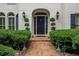 Elegant front entrance with brick walkway, mature boxwoods, exterior lanterns, and a black front door at 8480 Valemont Dr, Sandy Springs, GA 30350