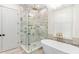 Elegant bathroom featuring a glass shower, soaking tub, and gold fixtures under a modern chandelier at 915 Laurel Brooke Ave, Peachtree City, GA 30269
