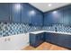 Stylish laundry room with blue cabinets, elegant backsplash, white countertops, and modern fixtures at 915 Laurel Brooke Ave, Peachtree City, GA 30269