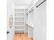 Bright walk-in closet with custom shelving, hanging rods, and hardwood floors at 915 Laurel Brooke Ave, Peachtree City, GA 30269