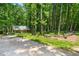 Exterior view of a charming log cabin nestled in a wooded area, with a gravel driveway at 1975 Mack Rd, Douglasville, GA 30135