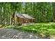 Charming log cabin featuring a stone chimney, metal roof, and inviting front porch, nestled amongst mature trees at 1975 Mack Rd, Douglasville, GA 30135