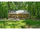 Quaint log cabin with a covered porch, offering a peaceful retreat surrounded by lush greenery and mature trees at 1975 Mack Rd, Douglasville, GA 30135