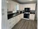 Bright kitchen featuring white cabinets, black countertops, stainless appliances, and vinyl floors at 6471 Ansley Blvd, Lithia Springs, GA 30122