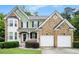 Charming two-story home boasts brick and green siding, plus an attached two-car garage and inviting front porch at 157 Spur Ln, Hiram, GA 30141