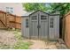 Backyard view of a grey storage shed with double doors, flanked by a wooden fence at 157 Spur Ln, Hiram, GA 30141
