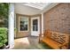 Inviting covered front porch featuring a wooden bench, brick accents, and a view of the landscaped yard at 1901 Brittania Cir, Woodstock, GA 30188