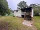 Backyard featuring grass, wooden stairs leading to a porch, and other mature trees at 29 Ivy St, Porterdale, GA 30014