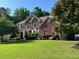 Charming brick home with a manicured lawn and mature trees showcasing classic architectural details at 4265 Lansmoore Xing, Suwanee, GA 30024
