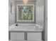 Elegant soaking tub with a window view, and a modern chandelier at 115 Township Ct, Woodstock, GA 30189