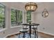 Bright breakfast nook featuring a modern light fixture, round table, and wooded backyard views at 115 Township Ct, Woodstock, GA 30189