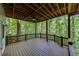 Large, covered patio area with ceiling fan overlooking the backyard woods at 115 Township Ct, Woodstock, GA 30189