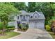 Charming gray two-story home with a well-manicured lawn, lush landscaping, and a two-car garage at 115 Township Ct, Woodstock, GA 30189