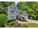 Two-story gray home featuring mature trees, lush landscaping, and a well-manicured lawn at 115 Township Ct, Woodstock, GA 30189