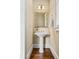 Charming powder room with a pedestal sink, decorative mirror, and hardwood floors at 2953 Kings Walk Ave, Marietta, GA 30062