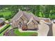 Aerial view of a brick home with an attached garage and a spacious driveway, surrounded by lush landscaping at 5009 Kingsley Manor Ct, Marietta, GA 30066