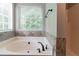 Corner tub with tile surround, window and dark fixtures at 1404 Lancaster Ct, Mcdonough, GA 30252