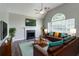 Cozy living room with leather sofas, fireplace, ceiling fan, and a large window, creating a warm and inviting space at 1404 Lancaster Ct, Mcdonough, GA 30252
