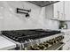 Close-up of modern stainless steel gas range and pot filler, complemented by marble backsplash at 3061 Bold Springs Rd, Dacula, GA 30019