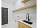 Laundry room with a sink, white marble flooring, floating shelves, and a black door at 3061 Bold Springs Rd, Dacula, GA 30019