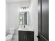 Stylish powder room featuring a black vanity cabinet, white countertop, and a modern light fixture above the rectangular mirror at 3061 Bold Springs Rd, Dacula, GA 30019