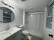 Well-lit bathroom featuring a walk-in shower, sleek vanity, round mirror, and modern fixtures at 453 James Street Sw, Lilburn, GA 30047