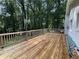 Wide, wooden deck featuring antique lamp posts and a view of a lush backyard surrounded by trees at 453 James Street Sw, Lilburn, GA 30047