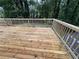 Exterior view of a spacious deck with wooden flooring surrounded by lush trees and antique lamp posts at 453 James Street Sw, Lilburn, GA 30047