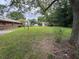 View of a large backyard with mature trees, a grassy lawn, and a glimpse of neighborhood homes at 1932 Pharrs Rd, Snellville, GA 30078