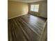 Living room featuring plank flooring, a white door, beige walls, and a window at 1932 Pharrs Rd, Snellville, GA 30078