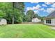 Expansive backyard with lush green grass, mature trees, wood fence, and storage shed at 5036 Weatherstone Drive, Buford, GA 30519