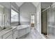 Bathroom with a large tub, glass-enclosed shower, double vanity, and light gray walls at 5036 Weatherstone Drive, Buford, GA 30519