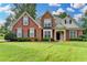 Charming two-story brick home with lush lawn, manicured landscaping, and classic black shutters at 5036 Weatherstone Drive, Buford, GA 30519