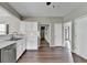 Kitchen with stainless appliances, wooden floors and white cabinets, showing hallway and stairway at 5036 Weatherstone Drive, Buford, GA 30519