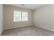Empty bedroom with plush carpet and a window offering natural light and outdoor views at 1496 Indian Forest Ct, Stone Mountain, GA 30083