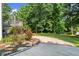 Landscaped backyard with a large grassy area, mature trees, and a charming concrete path at 2730 Samples Rd, Cumming, GA 30041